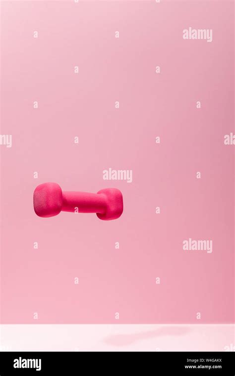 Pink Bright Dumbbell Levitating In Air On Pink Background Stock Photo