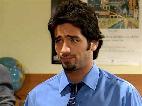 A Man Wearing A Blue Shirt And Tie Standing Next To Another Man In A Room