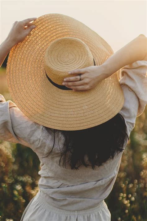 Stylish Boho Woman With Straw Hat Posing Among Wildflowers In Sunset