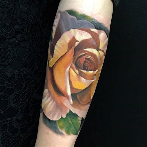 Realistic yellow rose tattoo on the left forearm.