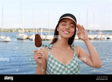 Beautiful Young Woman Holding Ice Cream Glazed In Chocolate Near River