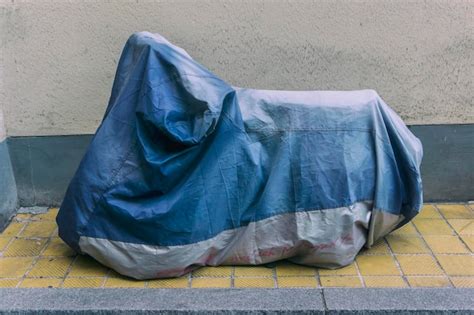 Premium Photo Motor Scooter Covered With Tarpaulin On Footpath By Wall