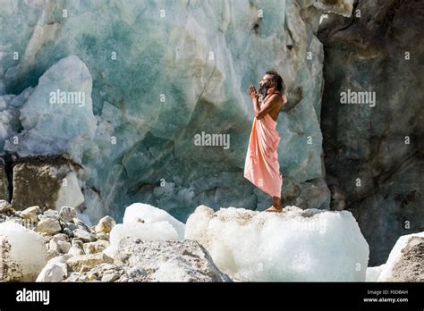 A Sadhu Holy Man Is Standing And Praying On A Block Of Ice At Gaumukh