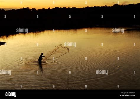 a fishing man during sunset Stock Photo - Alamy