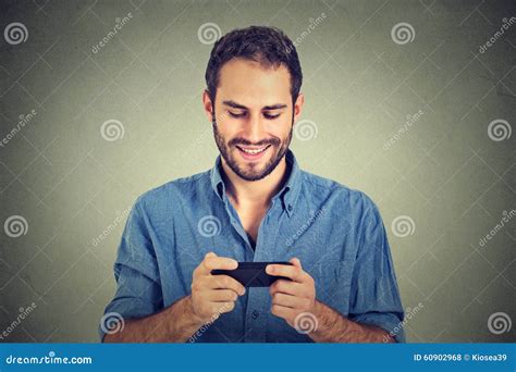 Smiling Man Looking At His Smart Phone While Text Messaging Or Watching