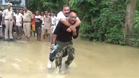 বন্যা কবলিত এলাকা দেখতে এসে উদ্ধারকর্মীর পিঠে চড়ে জল পেরোলেন অসমের