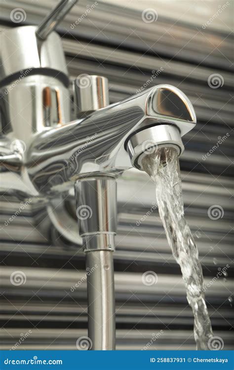 Water Flowing From Bath Tap Installed On Black And White Wall Stock