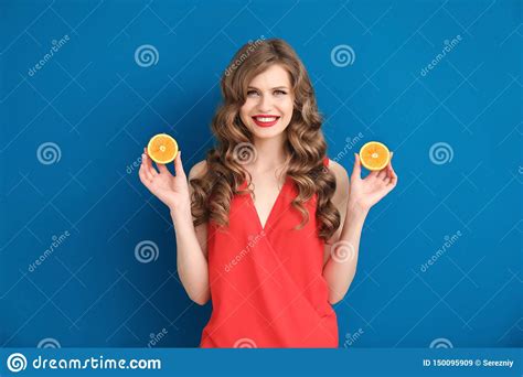 Mujer Joven Hermosa Con Mitades De La Naranja En Fondo Del Color Imagen