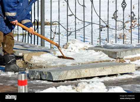 On A Clear Winter Day A Utility Worker Clears Snow And Ice From A