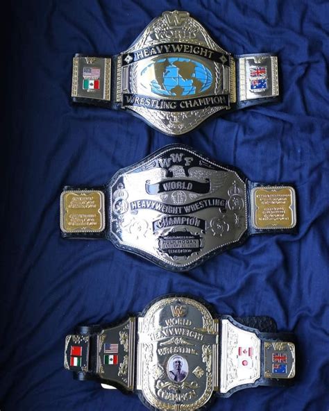 three different wrestling belts laying on top of a blue cloth covered ...