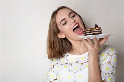 Premium Photo Pleased Woman Bites Tasty Chocolate Cake Over A Grey