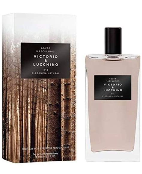 A Bottle Of Perfume Next To A Box With Trees In The Background And An