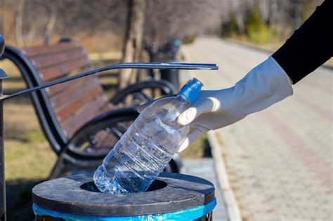 Joven voluntaria está tirando una botella de plástico en un basurero en