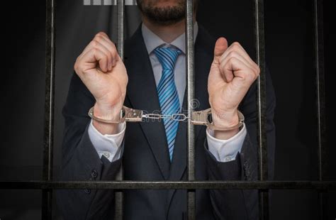 Businessman Or Politician With Handcuffs Behind Bars In Prison Cell