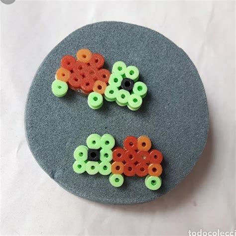 Two Plastic Beads Sitting On Top Of A Gray Plate With Green And Orange