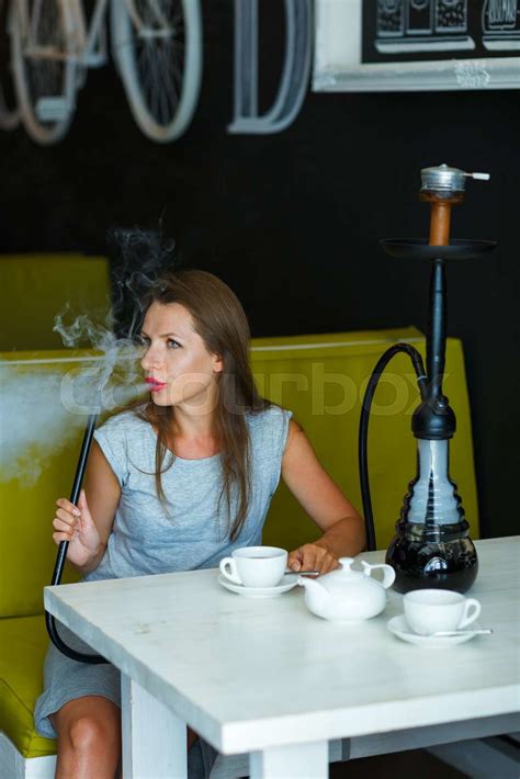 Beautiful woman smoking a hookah and drinking tea in a cafe | Stock ...