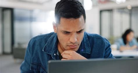 Pensando confundido y hombre en la computadora portátil escribiendo