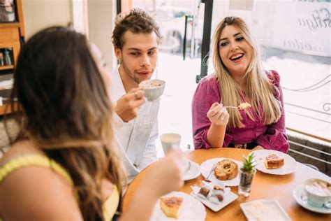 Jeunes Peuples Latins Assis Dans Un Café Buvant Du Café Avec Des Gâteaux Et écoutant Une