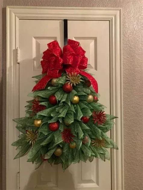 A Christmas Tree Made Out Of Leaves And Red Bows Hanging On A White