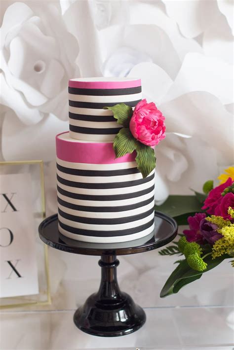 A Black And White Striped Cake With Pink Flowers On The Top Is Sitting