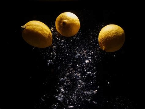 Limones Cayendo En Agua Con Salpicaduras Sobre Fondo Negro Foto Premium