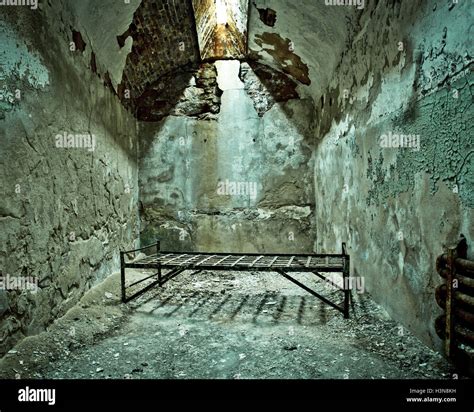 Crumbling abandoned prison cell with cot Stock Photo - Alamy