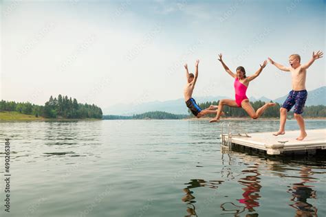 Group of kids jumping off the dock into the lake together during a fun ...