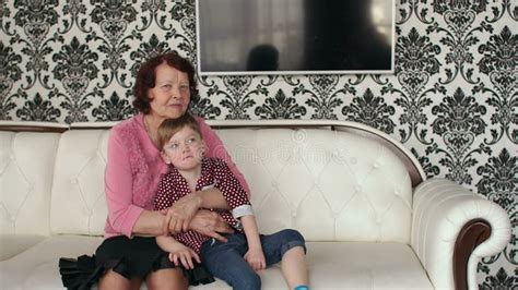 A Grandmother And Her Grandson Watch Tv Together Using The Remote Control Stock Footage