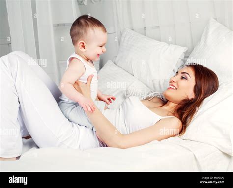 Feliz hermosa madre con su hijo de un año y medio en la cama en casa