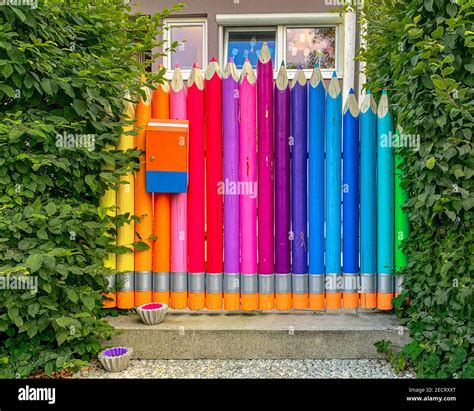 Wonderful Rainbow Colored Entrance Door Framed By Green Hedge Stock