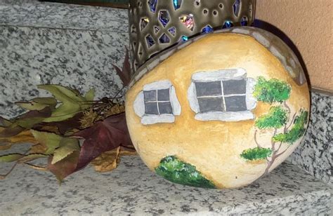 A Rock With A House Painted On It And A Potted Plant Next To It