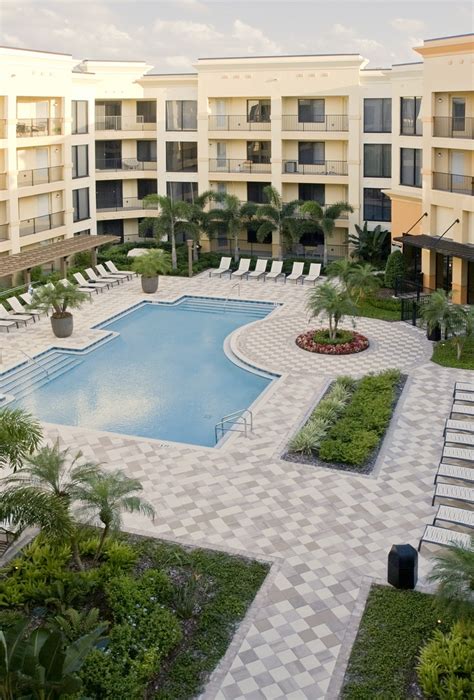 an outdoor swimming pool surrounded by lawn chairs and palm trees in ...