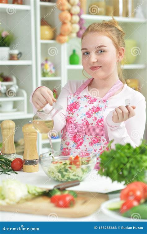 Portrait Of Cute Teen Girl Preparing Fresh Salad On Kitchen Table Stock