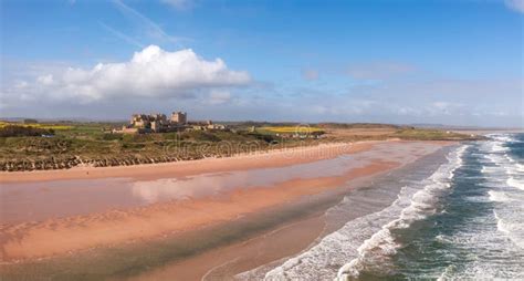 Aerial Panorama Landscape Of Bamburgh Castle And Sand Dunes In