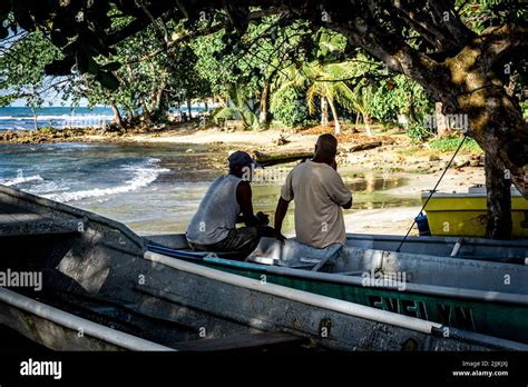 The Two Male Adults Sitting In A Boat On The Sandy Beach In Costa Rica