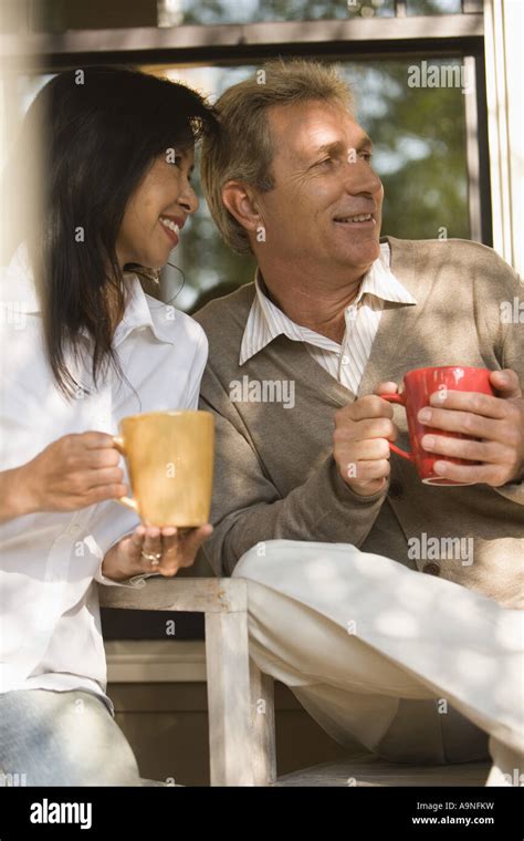 Mature Interracial Couple Holding Coffee Mugs Stock Photo Alamy