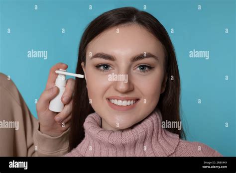 Man Spraying Medication Into Woman`s Ear On Light Blue Background Stock