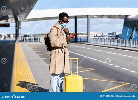 Afro American Millennial Traveler Man With Suitcase Stands In Airport