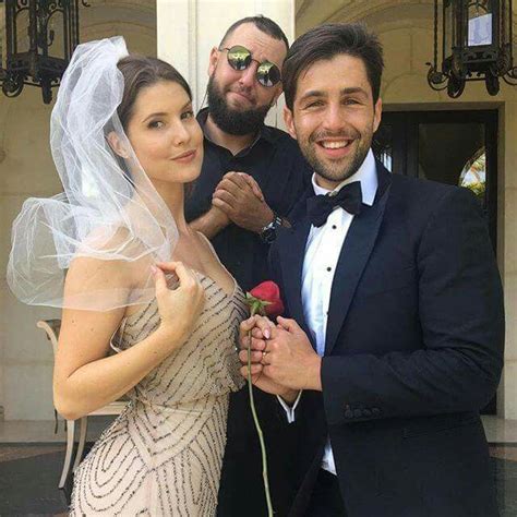 two men and a woman pose for a photo in front of a building wearing tuxedos