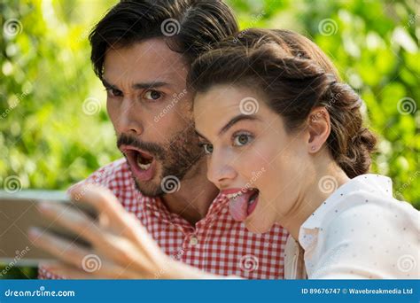 Playful Couple Taking Slefie Through Mobile Phone At Park Stock Image