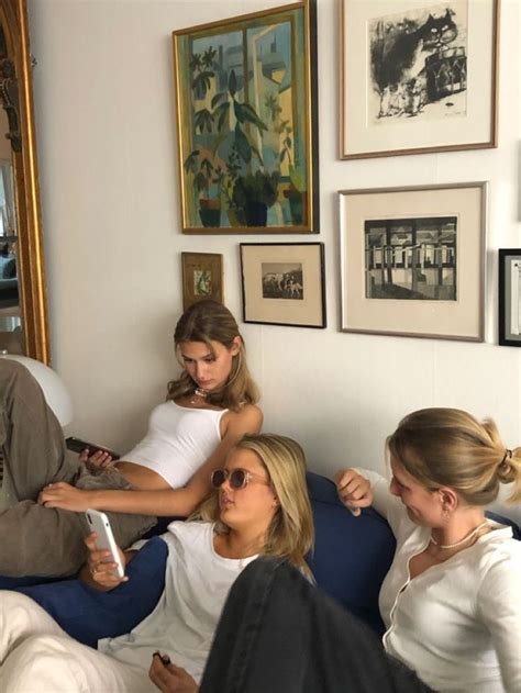 Three Women Sitting On A Couch In Front Of Pictures