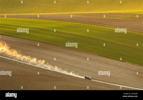 Car blowing up dust while driving down a rural road near a field Stock Photo - Alamy