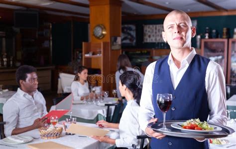 Hospitable Waiter Welcoming Guests In Cozy Restaurant Hall Stock Image