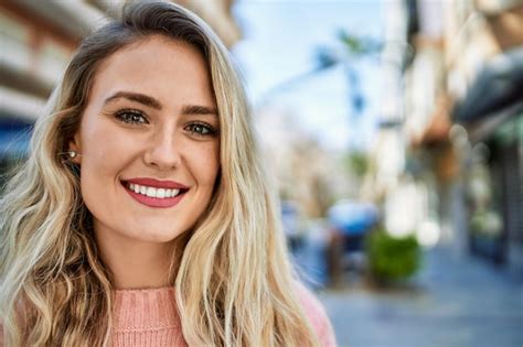 Jovem mulher loira sorrindo para a cidade Foto Grátis