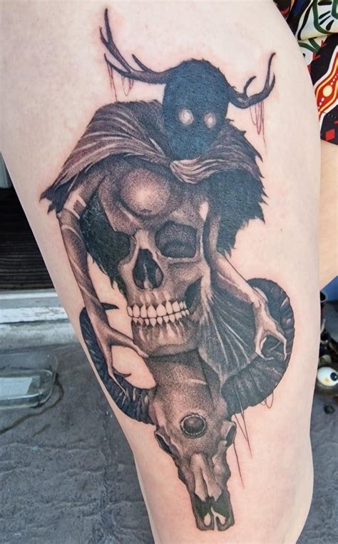 a woman's leg with a skull and demon tattoo on the side of her thigh