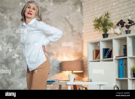 Mature Woman In The Office Suffering From Lower Back Pain Stock Photo