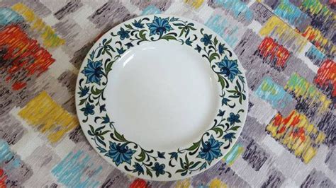 A White And Blue Plate Sitting On Top Of A Colorful Tablecloth Covered