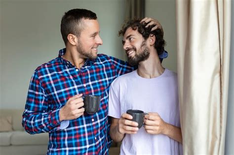 Joven pareja gay enamorada mirando por la ventana dos jóvenes hombres andróginos sonriendo