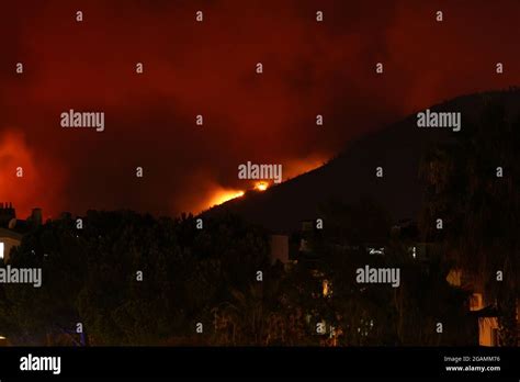 Smoke And Flames Rise From A Forest Fire Over Residential Buildings In