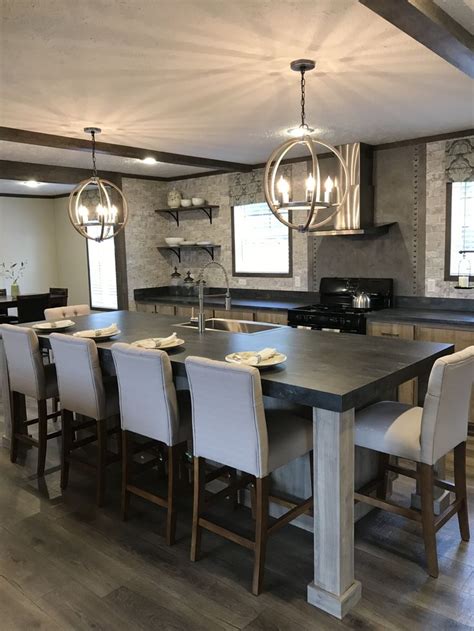 a dining room table and chairs with lights hanging from the ceiling in front of it